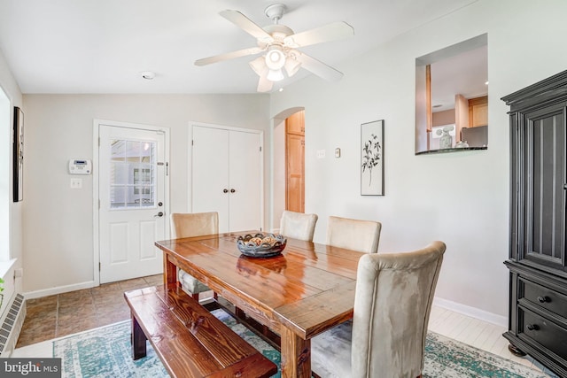 dining area with baseboards, a ceiling fan, arched walkways, and lofted ceiling