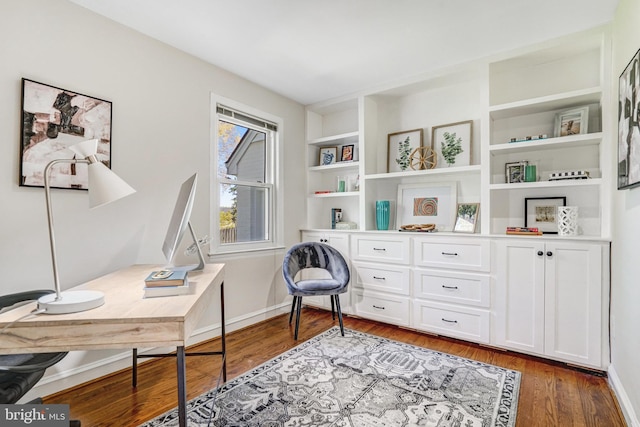 home office with built in shelves, baseboards, and wood finished floors