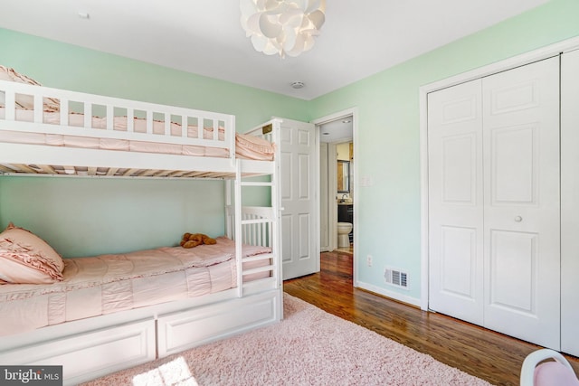 bedroom featuring a closet, visible vents, wood finished floors, baseboards, and a notable chandelier