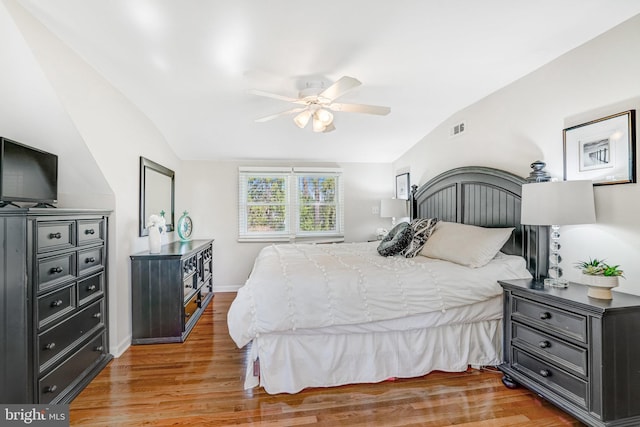 bedroom with light wood finished floors, visible vents, baseboards, and lofted ceiling