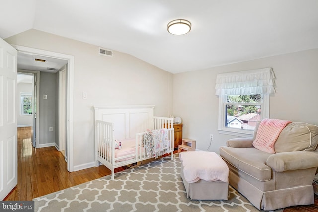 bedroom featuring wood finished floors, multiple windows, vaulted ceiling, and visible vents