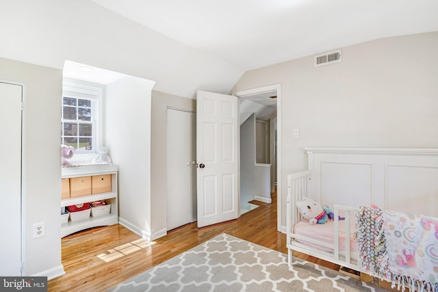 bedroom with visible vents, wood finished floors, and lofted ceiling