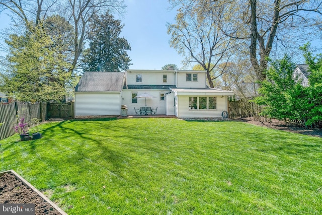 back of house with a fenced backyard and a lawn