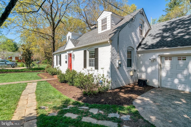 view of side of home featuring a yard, brick siding, driveway, and a shingled roof