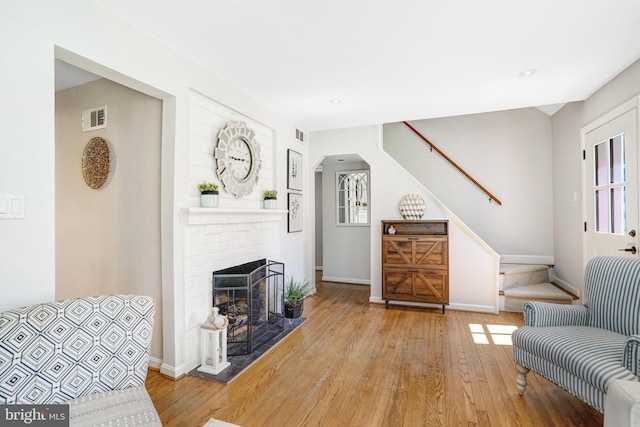 interior space featuring a fireplace, visible vents, stairway, wood finished floors, and baseboards