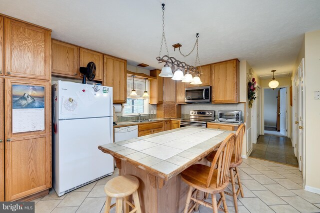 kitchen featuring a breakfast bar area, a center island, a toaster, tile countertops, and appliances with stainless steel finishes