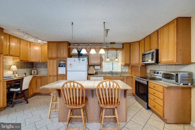 kitchen with a sink, a kitchen island, stainless steel appliances, tile countertops, and a toaster
