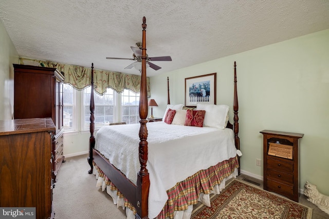 bedroom with baseboards, a textured ceiling, ceiling fan, and light carpet