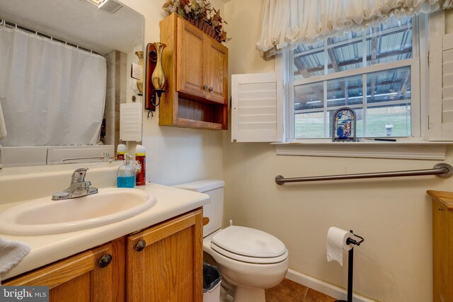 bathroom with toilet, tile patterned flooring, and vanity
