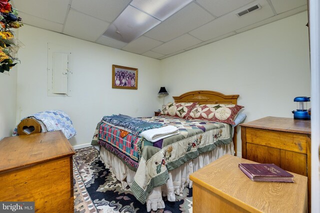 bedroom featuring electric panel, visible vents, and a paneled ceiling