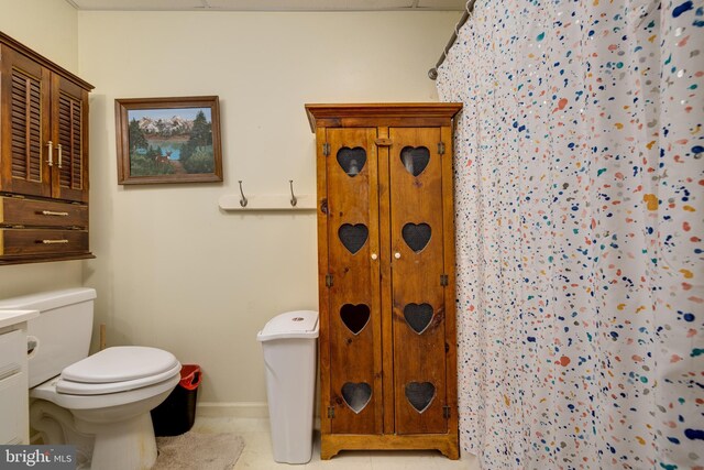 bathroom featuring baseboards, a closet, toilet, and tile patterned flooring