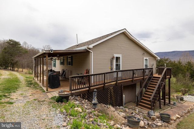 rear view of property featuring driveway, a shingled roof, a deck, and stairs
