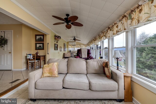 living area with vaulted ceiling, light tile patterned floors, baseboards, visible vents, and ceiling fan