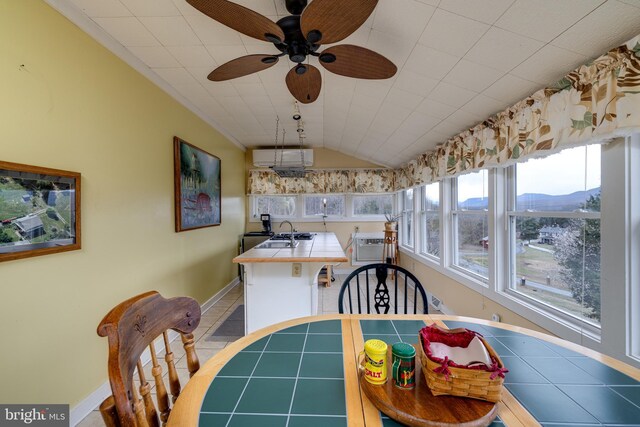 dining area with light tile patterned flooring, a wall mounted AC, baseboards, ceiling fan, and lofted ceiling