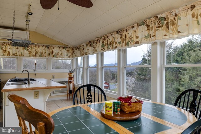 dining room featuring lofted ceiling, a mountain view, tile patterned floors, and a ceiling fan