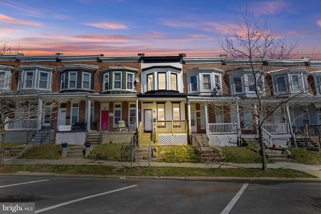townhome / multi-family property featuring uncovered parking and covered porch