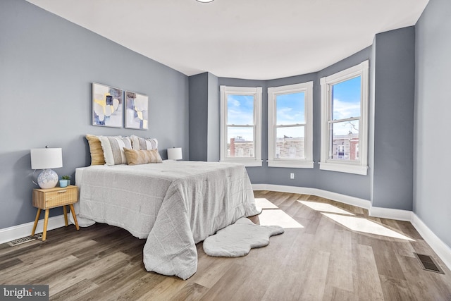 bedroom featuring visible vents, baseboards, and wood finished floors