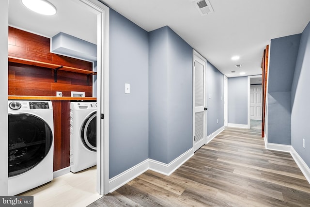 laundry room with separate washer and dryer, baseboards, light wood finished floors, and laundry area