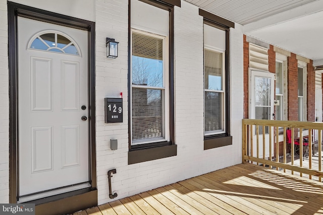 doorway to property with a porch and brick siding