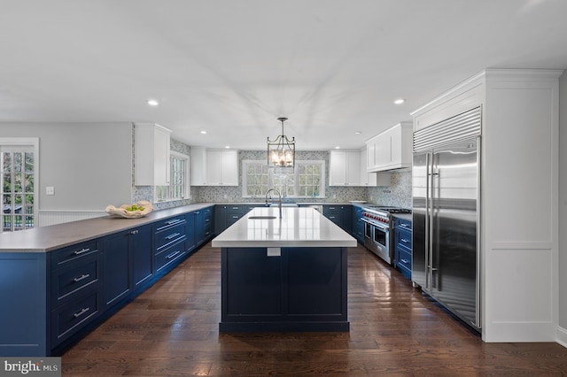 kitchen featuring backsplash, white cabinetry, blue cabinetry, light countertops, and high quality appliances