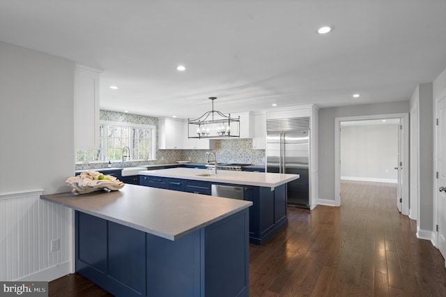 kitchen featuring light countertops, blue cabinetry, a peninsula, appliances with stainless steel finishes, and dark wood-style floors