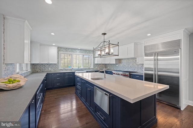 kitchen featuring tasteful backsplash, blue cabinets, stainless steel appliances, light countertops, and dark wood finished floors