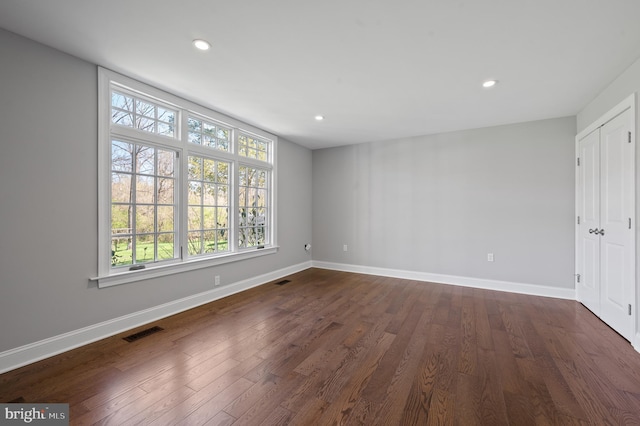unfurnished room featuring dark wood finished floors, baseboards, and visible vents