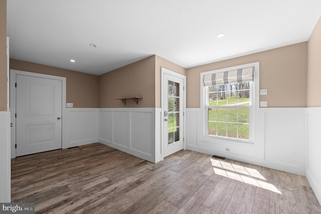 doorway to outside with a decorative wall, wood finished floors, a wainscoted wall, visible vents, and recessed lighting