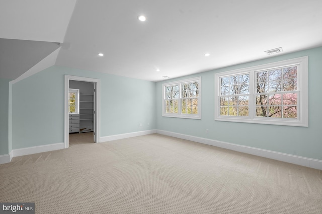unfurnished bedroom with recessed lighting, visible vents, light carpet, a walk in closet, and baseboards
