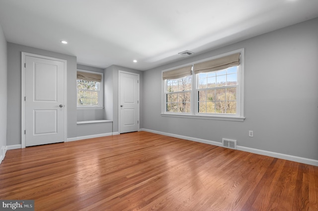 unfurnished bedroom with baseboards, wood finished floors, visible vents, and recessed lighting