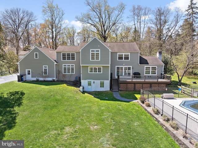 back of property with fence, a chimney, a yard, and a deck