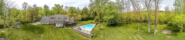 view of swimming pool featuring a wooded view, a yard, and a fenced in pool