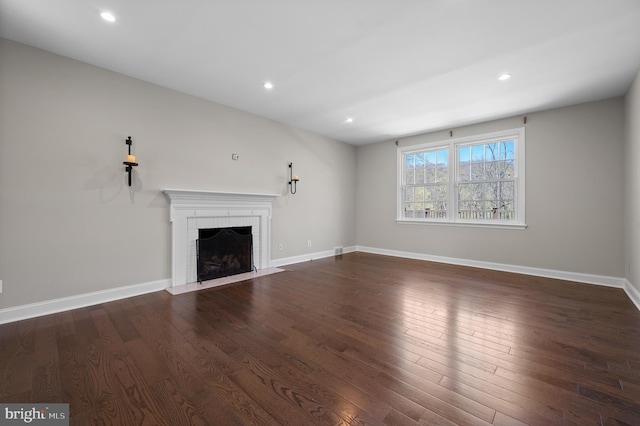 unfurnished living room featuring baseboards, a brick fireplace, dark wood-type flooring, and recessed lighting