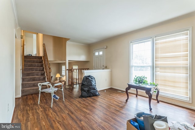 living area with visible vents, wood finished floors, baseboards, ornamental molding, and stairs