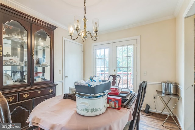 dining area with crown molding, wood finished floors, baseboards, a chandelier, and french doors
