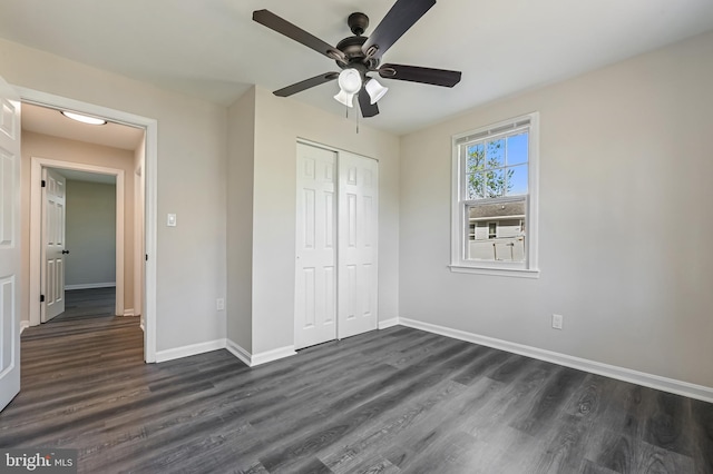 unfurnished bedroom with ceiling fan, a closet, baseboards, and dark wood-style flooring