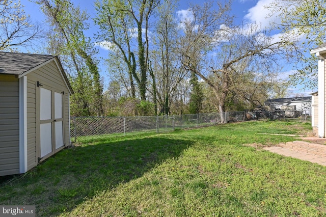 view of yard with a fenced backyard, a storage unit, and an outbuilding