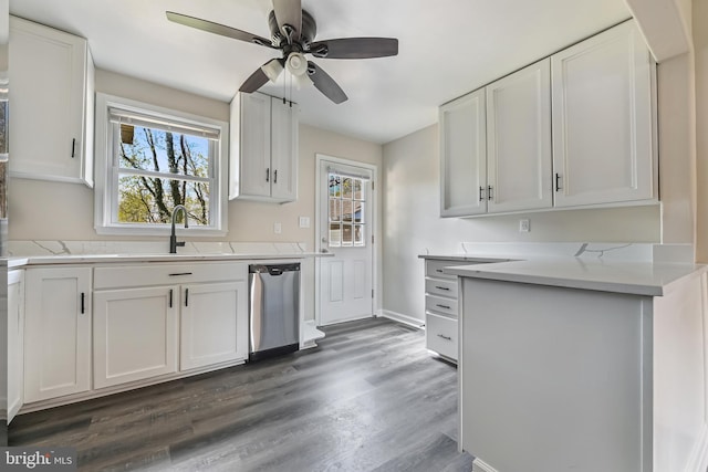 kitchen featuring dark wood finished floors, stainless steel dishwasher, a sink, and white cabinets