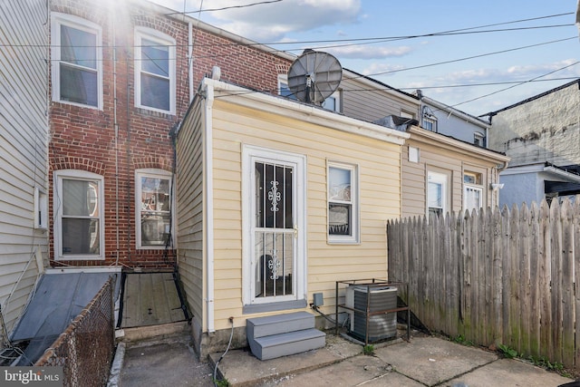 rear view of property featuring cooling unit, entry steps, and fence