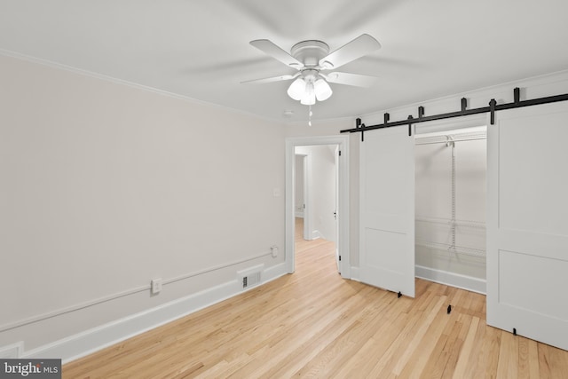 512 Dunlap St, Winchester, VA 22601 - unfurnished bedroom with a barn door, light wood-type flooring, ornamental molding, a closet, and ceiling fan