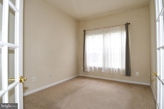 carpeted empty room featuring baseboards