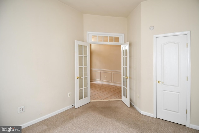 carpeted empty room featuring french doors and baseboards