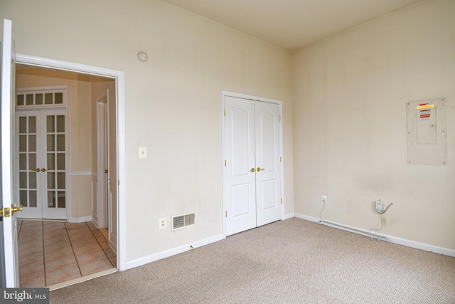 unfurnished bedroom featuring french doors, visible vents, carpet, and electric panel