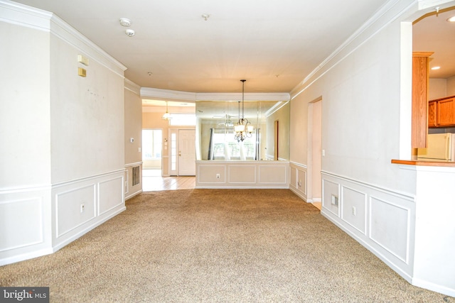 unfurnished dining area featuring a decorative wall, ornamental molding, a wainscoted wall, a chandelier, and light carpet