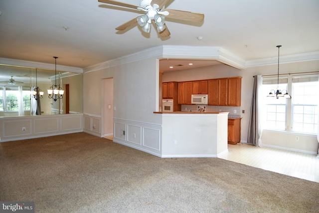 unfurnished living room with a wealth of natural light, light colored carpet, and ceiling fan with notable chandelier
