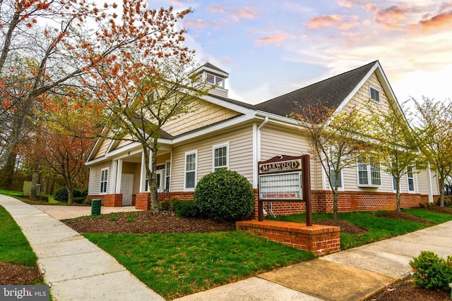 view of front of house featuring a yard and a shingled roof