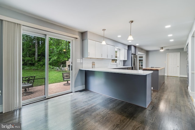 kitchen featuring a peninsula, recessed lighting, dark wood finished floors, stainless steel fridge, and baseboards