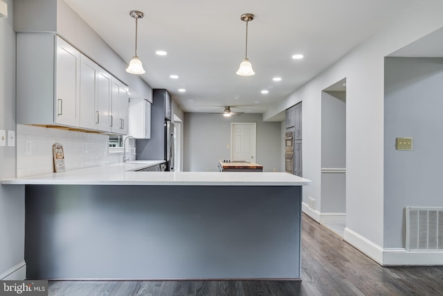 kitchen featuring a peninsula, a sink, dark wood finished floors, visible vents, and ceiling fan