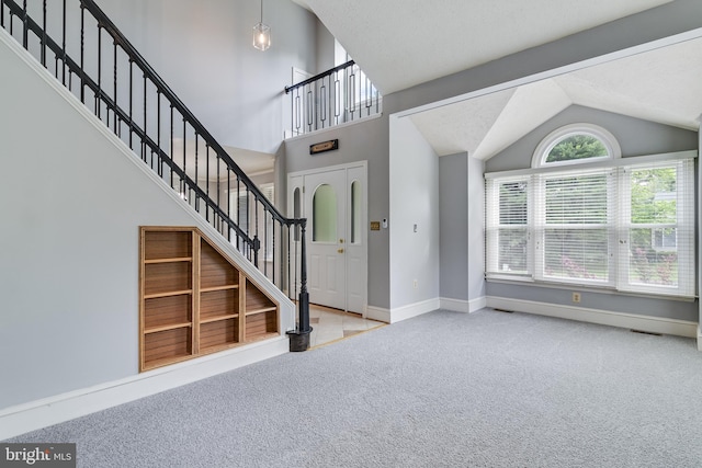 carpeted entryway with lofted ceiling, stairway, and baseboards