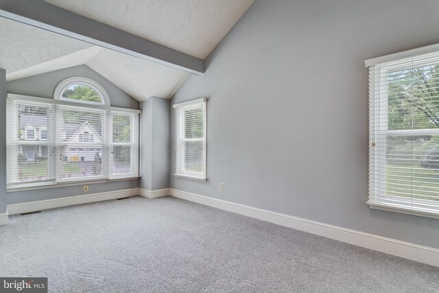 empty room with lofted ceiling with beams, carpet floors, baseboards, and visible vents